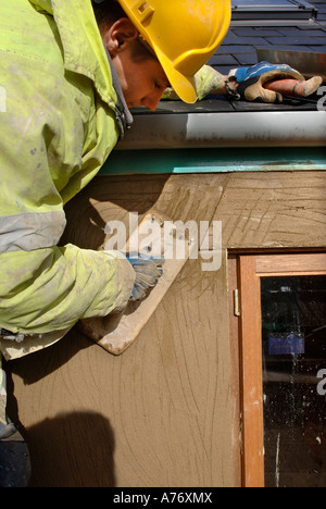 EIN GIPSER RENDERING UM NEUE HARTHOLZ FLÜGELFENSTER AUF EINER HÜTTE UNTER RENOVIERUNG UK Stockfoto