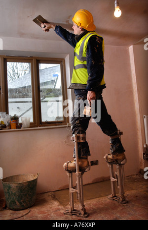 EIN GIPSER AUF STELZEN SKIMMING EINE DECKE AUF EINER HÜTTE UNTER RENOVIERUNG UK Stockfoto