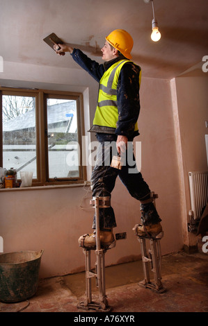 EIN GIPSER AUF STELZEN SKIMMING EINE DECKE AUF EINER HÜTTE UNTER RENOVIERUNG UK Stockfoto