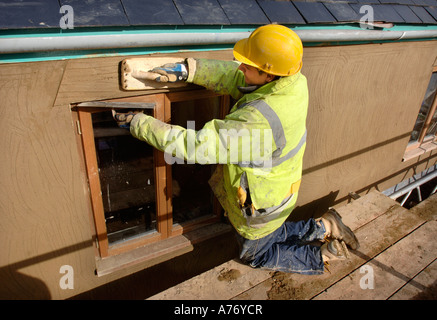 EIN GIPSER RENDERING UM NEUE HARTHOLZ FLÜGELFENSTER AUF EINER HÜTTE UNTER RENOVIERUNG UK Stockfoto