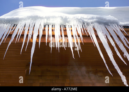 Eiszapfen hängen von einem Dach vor einem blauen Himmel. Stockfoto
