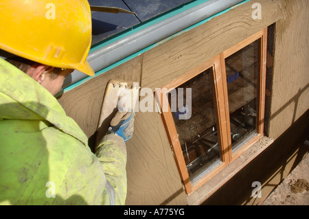 EIN GIPSER RENDERING UM NEUE HARTHOLZ FLÜGELFENSTER AUF EINER HÜTTE UNTER RENOVIERUNG UK Stockfoto