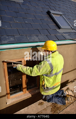 EIN GIPSER RENDERING UM NEUE HARTHOLZ FLÜGELFENSTER AUF EINER HÜTTE UNTER RENOVIERUNG UK Stockfoto