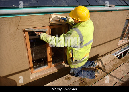 EIN GIPSER RENDERING UM NEUE HARTHOLZ FLÜGELFENSTER AUF EINER HÜTTE UNTER RENOVIERUNG UK Stockfoto