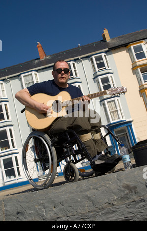 behinderte Menschen im Rollstuhl Gitarre spielen in der Sonne auf Aberystwyth Promenade Sommernachmittag Wales UK Stockfoto