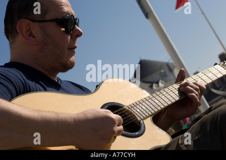 Mann spielt Gitarre in Aberystwyth Promenade am Meer sonnigen Sommernachmittag Wales UK Stockfoto