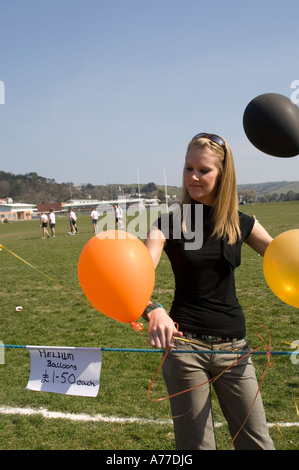 junge Frau Verkauf von Orangen und gelben Helium gefüllte Ballons für Charity Fundraising-Event UK Stockfoto