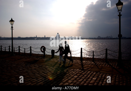 Ein paar gehen hand in hand entlang der Docks neben den Fluss Mersey in Liverpool UK Stockfoto