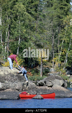 VATER UND SOHN AUFSTIEG FELSEN AUF EINEM SEEUFER IN DER GRENZE GEWÄSSER KANU-BEREICH WILDNIS, NORDMINNESOTA. FALLEN. Stockfoto