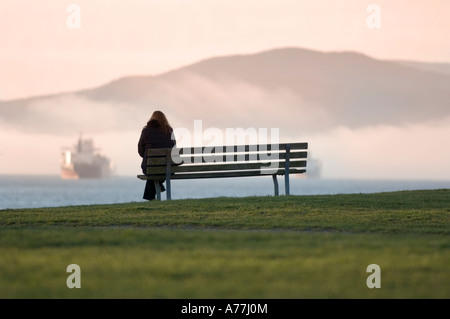 einsame Figur sitzt auf öffentlichen Parkbank Kitsilano Beach mit Blick auf English Bay Vancouver Kanada genießen der Natur in der Stadt Stockfoto