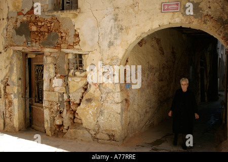 Westlichen Kreta eine alte kretische Frau zu Fuß vorbei an einer verfallenen venezianischen Haus in der Altstadt von Chania Stockfoto