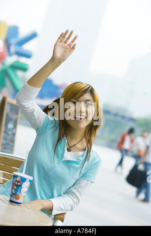 Teenager-Mädchen sitzen im Freien, winken Stockfoto