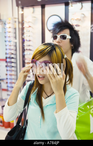 Teenager-Paar Sonnenbrillen im Laden anprobieren Stockfoto