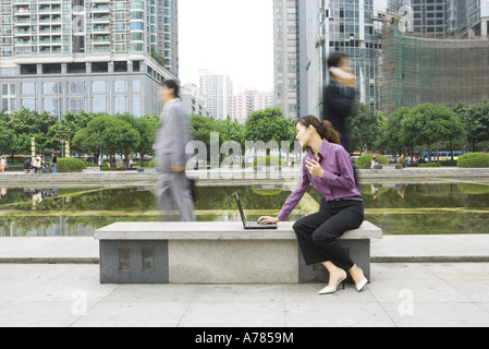 Junge Frau mit Laptop im Freien auf Office Parkbank Stockfoto