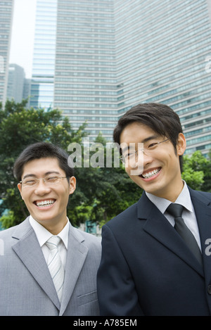 Zwei junge Unternehmer, lachen, Bürogebäude im Hintergrund Stockfoto