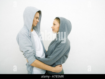 Junges Paar tragen Kapuzen-Sweatshirts, halten einander um Taille, von Angesicht zu Angesicht Stockfoto