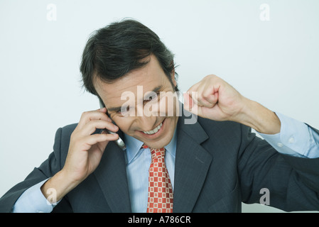 Geschäftsmann mit Handy, lächelnd, und Faust machen Stockfoto