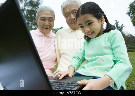 Mädchen mit Laptop Großeltern schauen Stockfoto