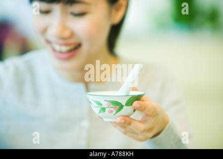 Frau hält Schüssel Suppe mit Löffel, Fokus auf Schüssel im Vordergrund Stockfoto