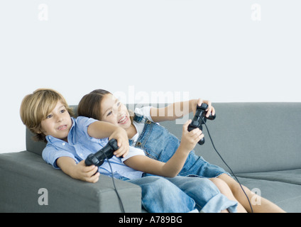 Jungen und Mädchen Video Spiel durchhalten Joysticks auf sofa Stockfoto