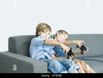 Jungen und Mädchen Video Spiel durchhalten Joysticks auf sofa Stockfoto