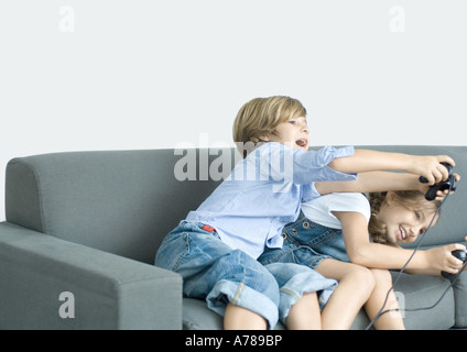 Jungen und Mädchen Video Spiel durchhalten Joysticks auf sofa Stockfoto