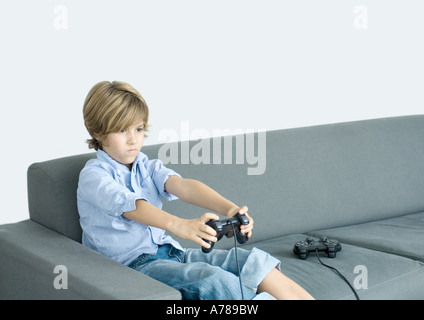 Junge sitzt auf der Couch spielen video-Spiel, finster Stockfoto