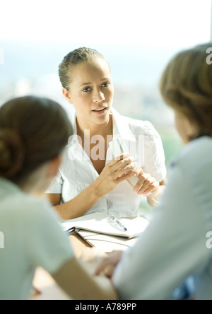 Junges Paar sitzt über Tisch von jungen weiblichen professionellen Betrieb Telefon Stockfoto