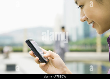 Geschäftsfrau mit Messaging-Handy, lächelnd, Nahaufnahme, seitliche Ansicht Stockfoto