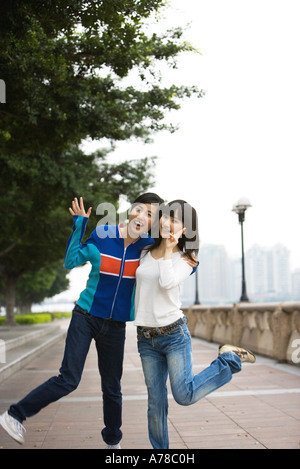 Zwei junge Erwachsene Freundinnen, beide munter ein Bein Stockfoto