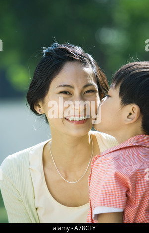 Junge Mutter auf Wange, Frau lächelt in die Kamera, küssen Nahaufnahme Stockfoto