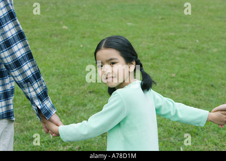 Mädchen auf der Suche über die Schulter, lächelt in die Kamera Stockfoto