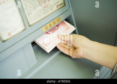 Person, die Banknoten von ATM-Maschine, verkürzte Ansicht Stockfoto