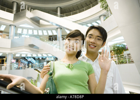 Paar nehmen Rolltreppe in der Shopping Mall, Frau winken Stockfoto