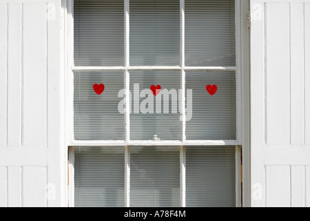 drei rote herzförmige Aufkleber auf Schiebefenster Stockfoto