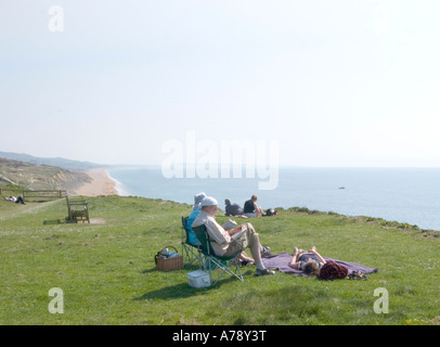 Sonnenanbeter von Bank Holiday entspannen sich in der Sonne auf den Klippen von Burton Bradstock, Dorset neben dem South West Coast Path, England, Großbritannien Stockfoto