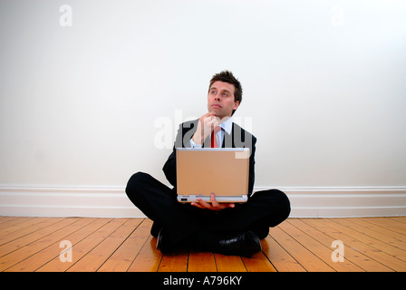 Junger Geschäftsmann saß cross legged denken Stockfoto