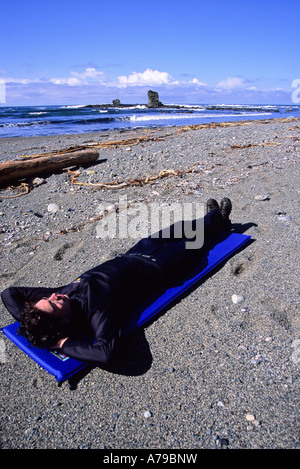 Ein Mann 20 25 nimmt eine Pause vom Wandern an Bonilla Punkt auf der West Coast Trail in der Nähe von Carmanah Creek im Pacific Rim National Park Stockfoto