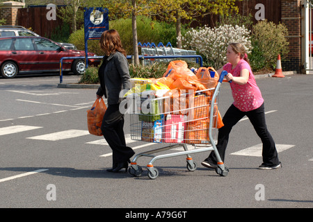 Teenager weiblich schieben einen Einkaufswagen voller Lebensmittel. Stockfoto