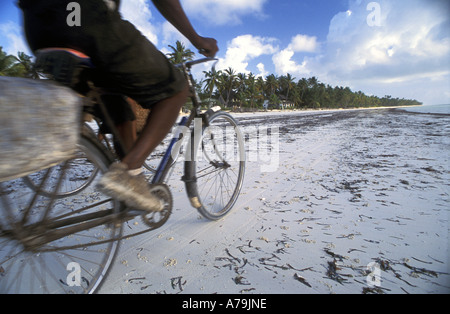 Lokale Mann reitet alten Fahrrad entlang des Strandes in Bwejuu Sansibar Tansania Stockfoto