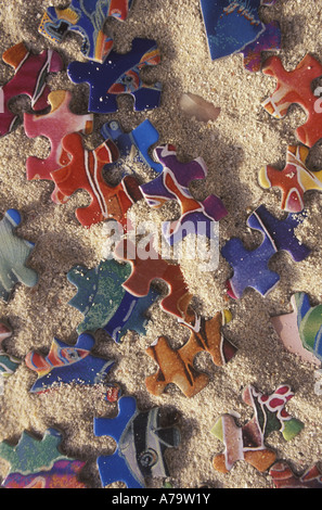 Sortiment mit bunten Puzzleteilen in Sand. Stockfoto