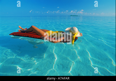 Frau in einem Traum auf klaren ruhigen Aqua Wasser mit Insel am fernen Horizont schwebend Stockfoto
