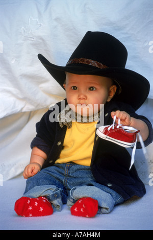 Kind 7-12 Monate mit großen Cowboy-Hut und roten Socken und Schuhe Stockfoto