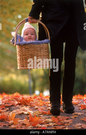 Mutter, nehmen ihr Baby in einem Korb für Spaziergang im Herbst Stockfoto