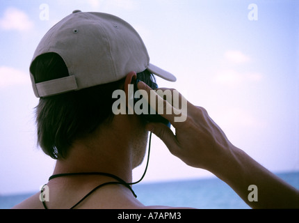 Heckansicht des junger Mann mit Handy am tropischen Strand Stockfoto
