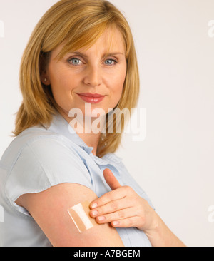 ATTRAKTIVE GESUNDEN JUNGEN BLONDEN FRAU ANWENDUNG TRANSPARENT NIKOTIN PATCH ARM Stockfoto