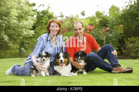 Frau und Mann mit Australian Shepherd einen Welpen auf Wiese Stockfoto