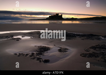 Der Umriss des Bamburgh Castle angesehen vom Strand im Licht frühen Morgens Stockfoto