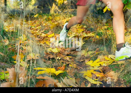 Junge Frau von der Taille abwärts Joggen in Herbstfarben gesehen Stockfoto