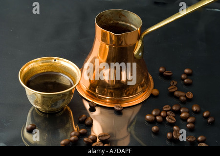 Traditionelle türkische Kupfer-Kaffeekanne und Tasse und Kaffeebohnen auf einem glänzenden schwarzen Hintergrund mit Reflexion Stockfoto